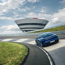 Ein fahrender blauer Porsche Taycan auf der Porsche Leipzig Rundstrecke.